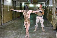 Naked prisoner stands before a US soldier